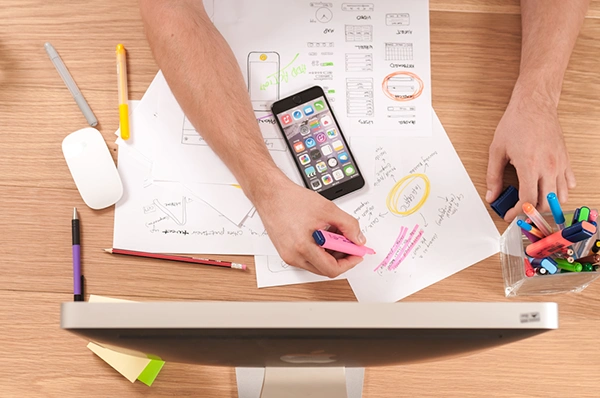 A person at a desk using a computer and cell phone, focused on marketing strategies for diverse audiences through segmentation