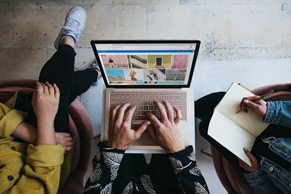 Three people on a couch, focused on their laptops, collaborating on how to use customer segmentation.
